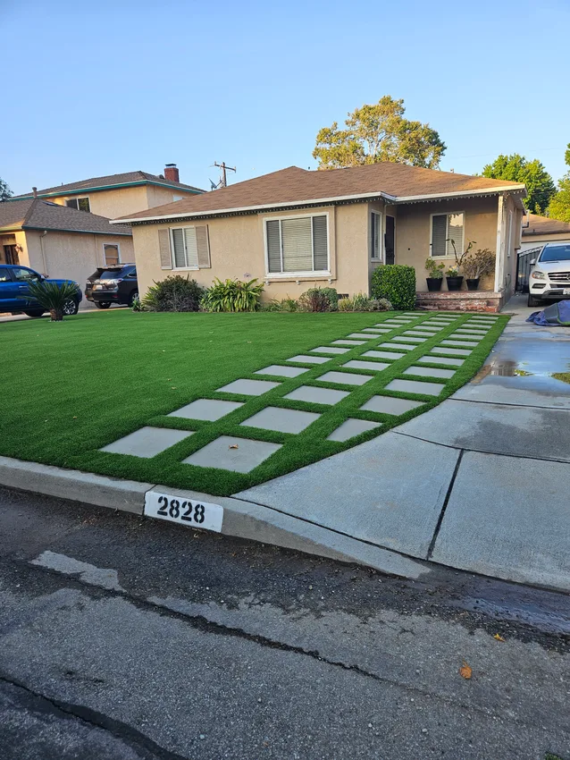Front yard with artificial turf and a grid of concrete stepping stones leading to a home